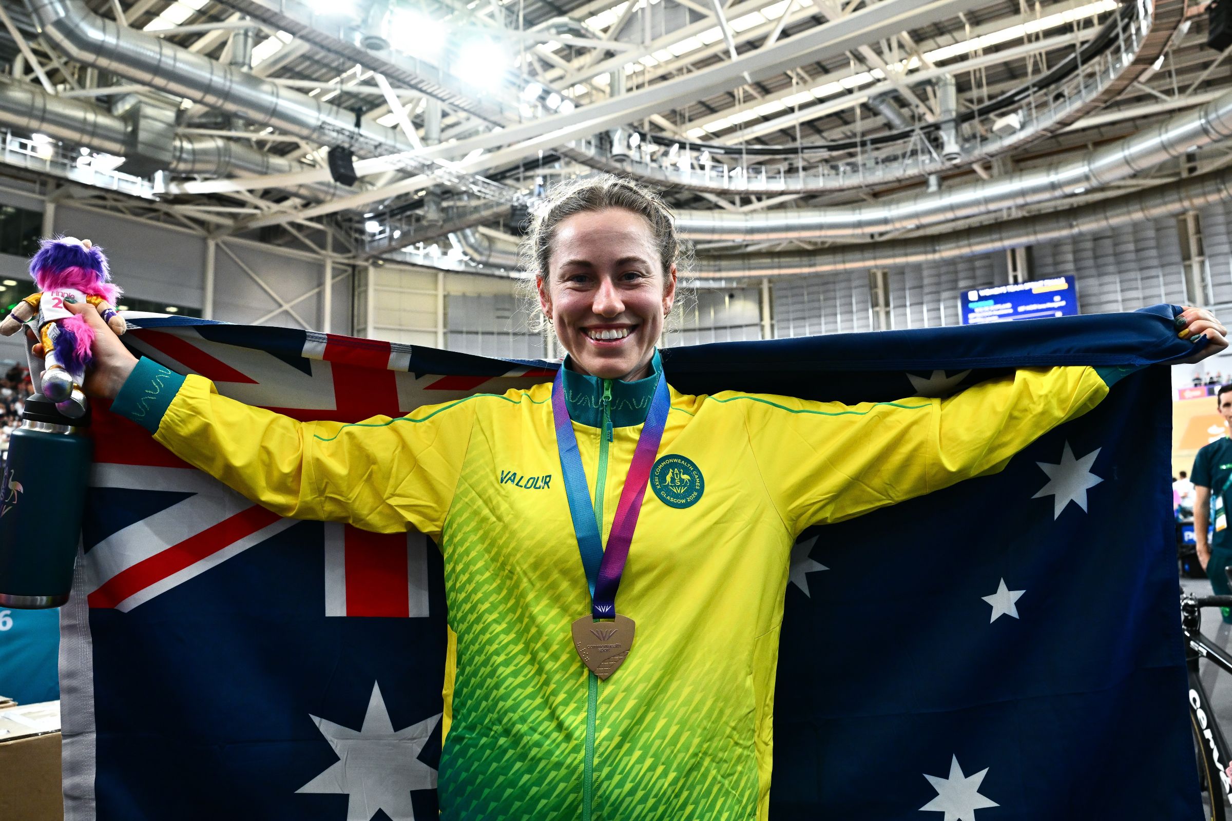 Tara Neyland celebrates with gold medal and Australian flag after winning the C4−C5 Women’s Individual Pursuit at the 2026 Commonwealth Games in Glasgow, Scotland.